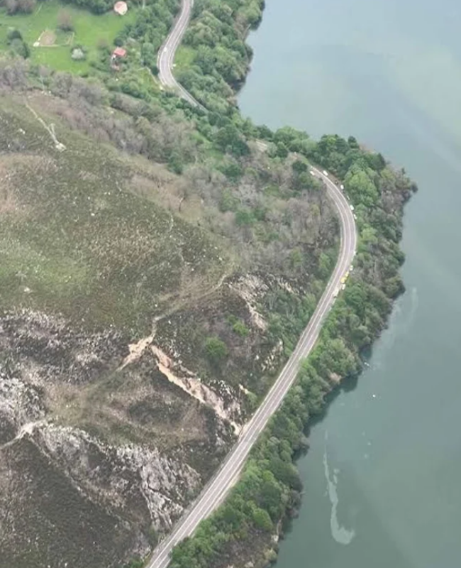 Dos manchas de aceite marcan la zona en la que el helicóptero se sumergió en las aguas del embalse de Tanes, cuya aportación a la red de agua potable de Asturias se ha cortado por seguridad. En la zona superior de la foto, la localidad casina de Tanes.