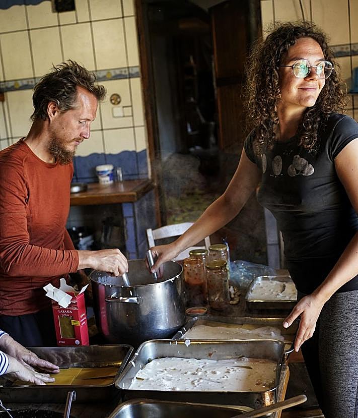 Imagen secundaria 2 - Una residente con uno de los corderos de la ecoaldea. La francesa Silvie, de vuelta en su casa tras hacer compost con estiércol, junto a Ibon, estudiante pamplonés que está haciendo aquí prácticas de ganadería. El suizo Maiitrico y la valenciana Laura preparando la comida comunal.