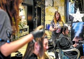 Ainara Cermeño, propietaria de la peluquería Im Miu, en el Ensanche bilbaíno, corta el pelo a una clienta.