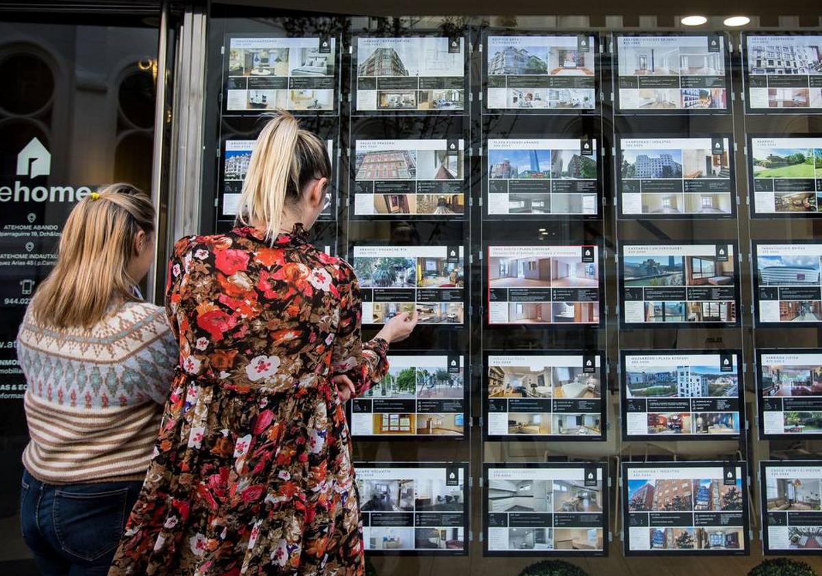 Dos mujeres observan los anuncios de una inmobiliaria en Bilbao.