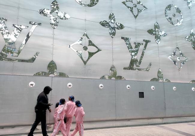 Un grupo pasa por delante del edificio de Louis Vuitton con forma de baúl
