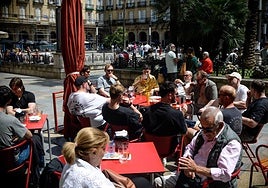 Un grupo de turistas repone fuerzas en la Plaza Nueva disfrutando del buen tiempo que hubo ayer en Bilbao.