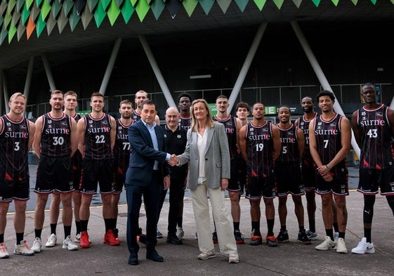 Xabier Sagredo, presidente ejecutivo de BBK, e Isabel Iturbe, presidenta del Bilbao Basket, se estrechan la mano frente a la plantilla, con Miribilla a sus espaldas.