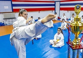 Maddi Barona realiza un movimiento de kárate ante el trofeo.