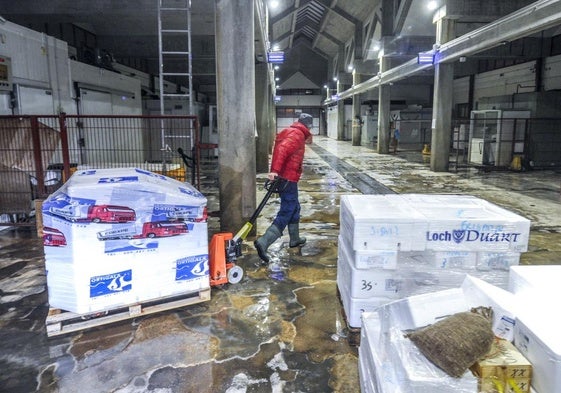 Un pescatero se lleva unas cajas a su camión.