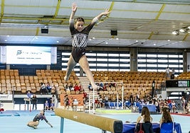 Una gimnasta realiza un ejercicio en la barra de equilibrio.