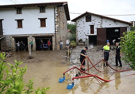 Operarios municipales y vecinos con las bombas de desagüe en una zona de baserris afectada en Lazkao.