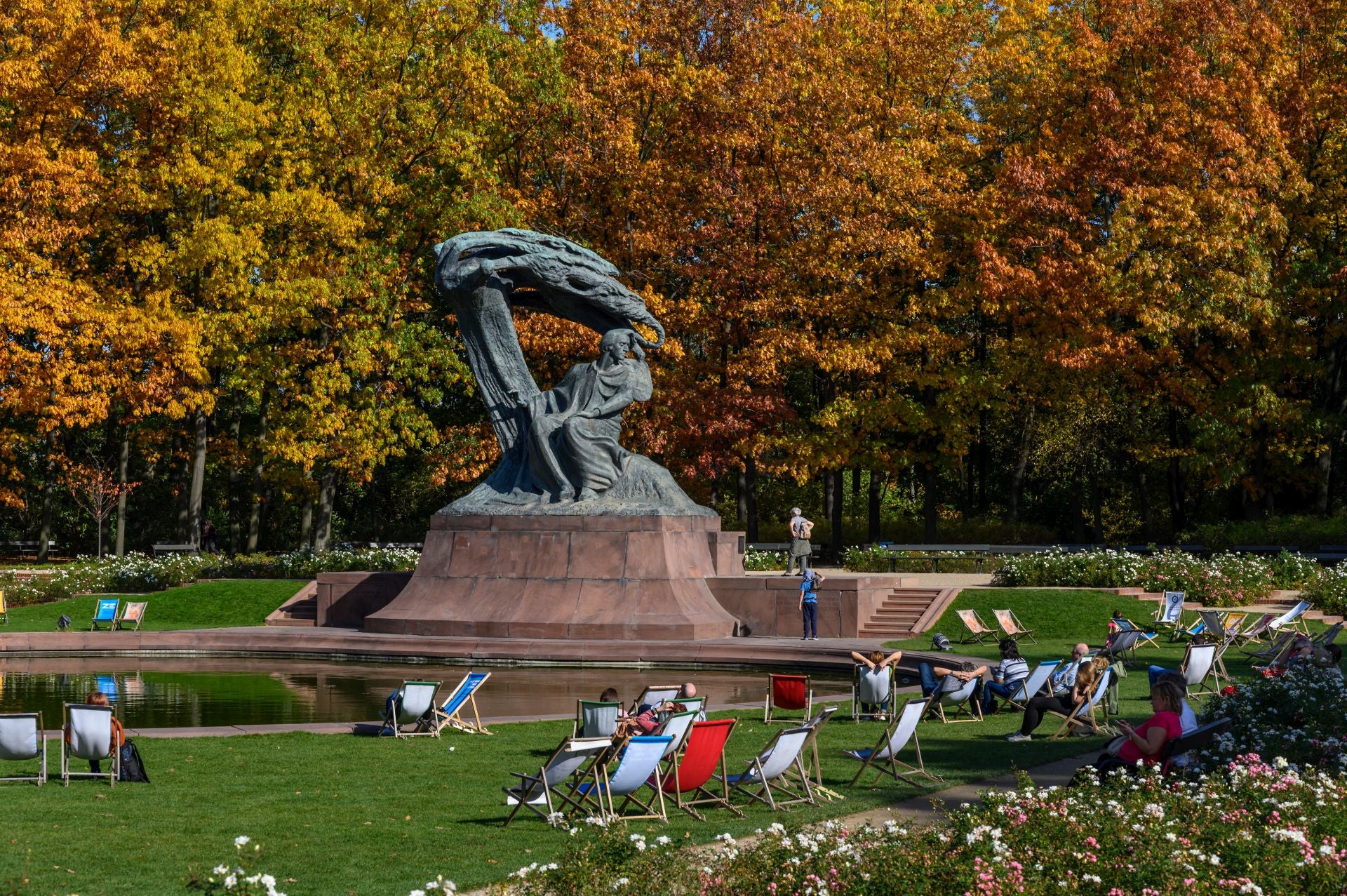 Varias personas descansan ante la escultura de Chopin en el Parque Łazienki.