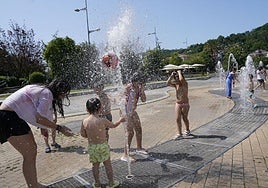 Niños y adultos se resfrescan en una fuente en Abandoibarra en un día de calor.