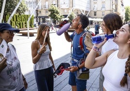 Ungrupo de turistas se refresca en la plaza de la Virgen Blanca.