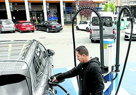 Un hombre recarga su vehículo eléctrico en una estación