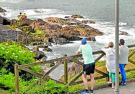 Paseantes siguen las labores de rescate del joven accidentado ayer en la costa de Mundaka