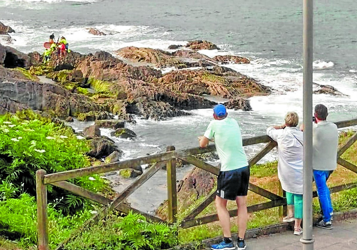 Paseantes siguen las labores de rescate del joven accidentado ayer en la costa de Mundaka