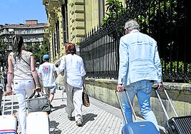 Dos turistas arrandan sendas maletas por una calle del centro de San Sebastián