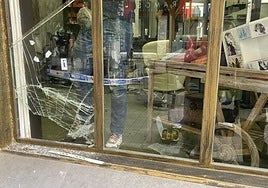 Un policía local toma fotografías del hueco por el que se coló el ladrón.