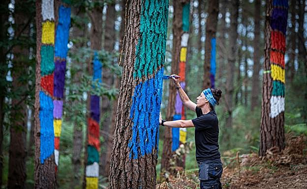 Una artista repara una de las pinturas del bosque de Oma, la obra más popular de Ibarrola.