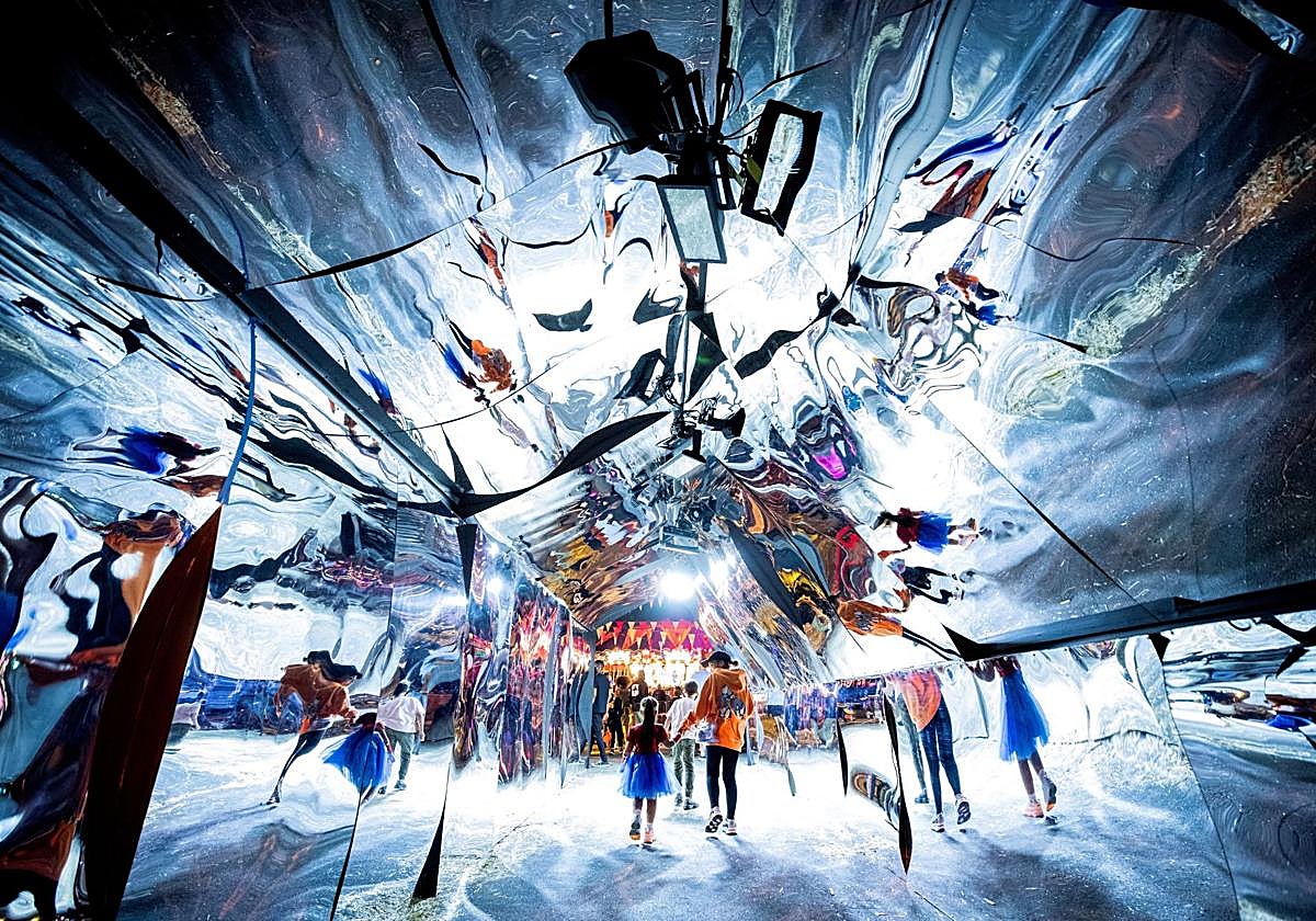 Asistentes caminan a través de un túnel de espejos en Los Ángeles.