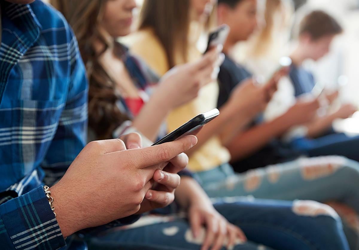 Estudiantes de instituto utilizando sus teléfonos móviles.