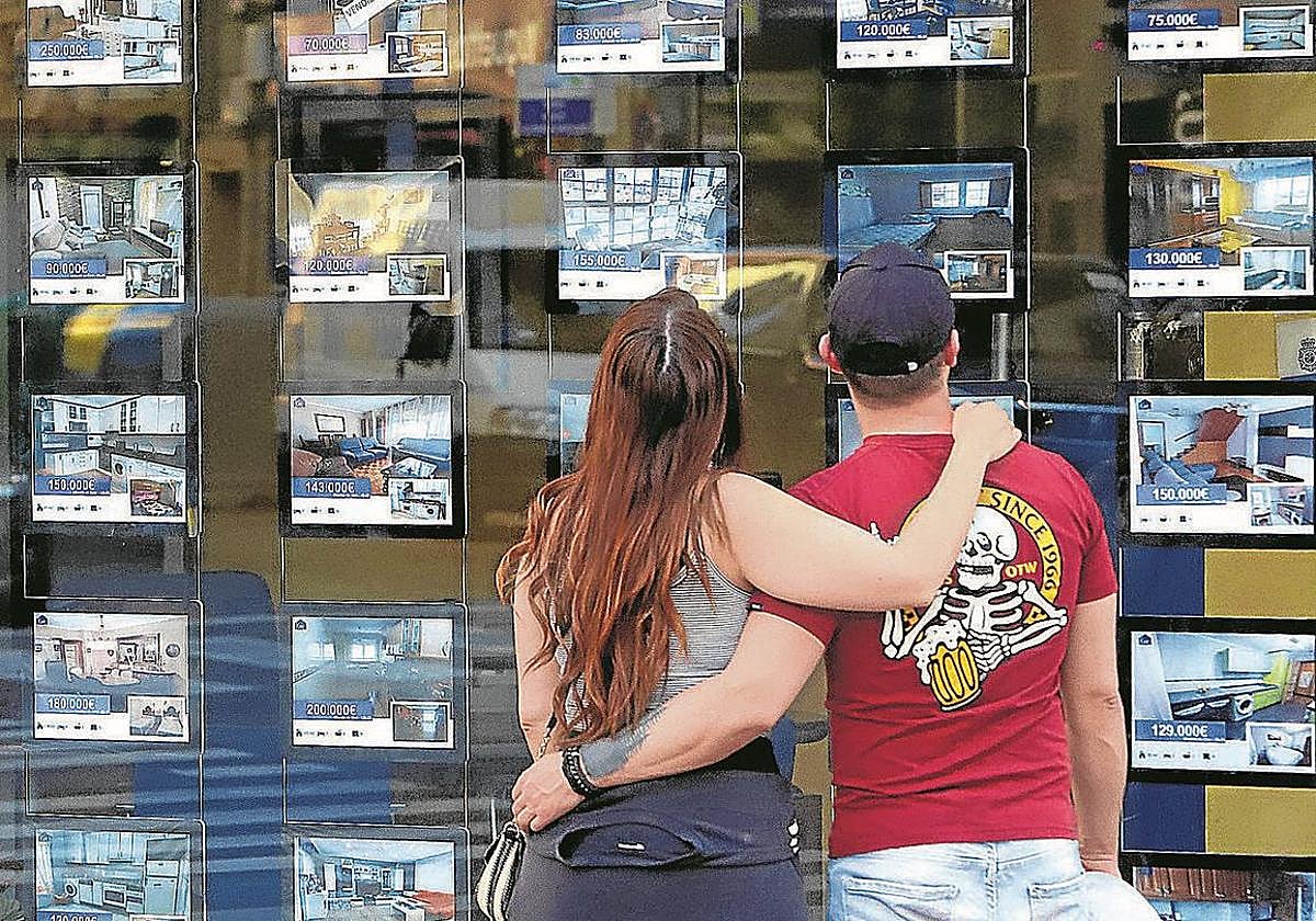 Una pareja joven contempla ofertas de viviendas a la venta.