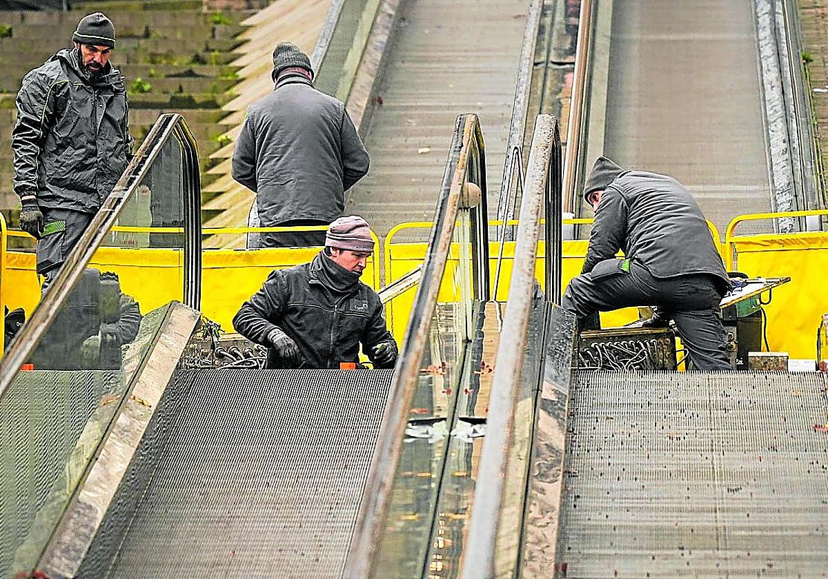 Unos operarios arreglan las escaleras mecánicas en un cantçon del Casco Viejo