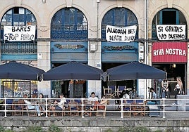 Clientes en las terrazas del Muelle de Marzana, bajo los carteles reivindicativos de los vecinos.