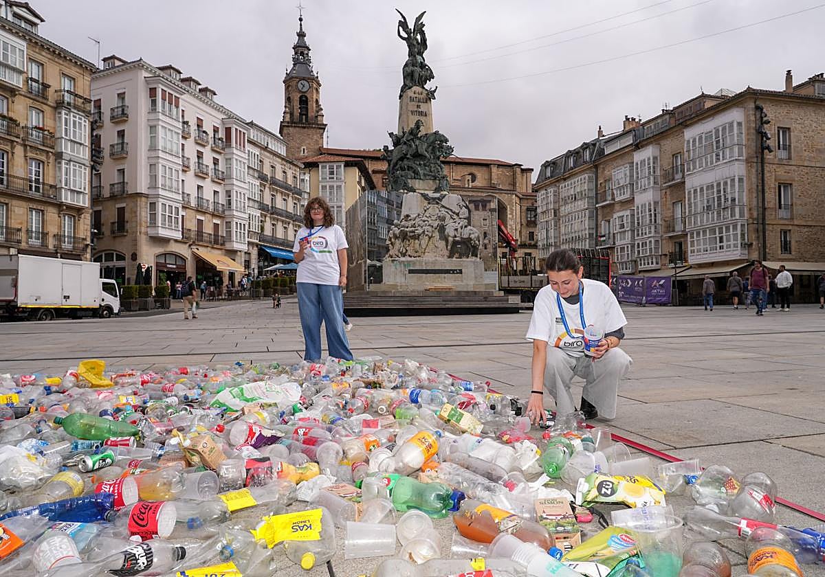 Dos voluntarias en la representación de residuos plásticos frente a la Virgen Blanca
