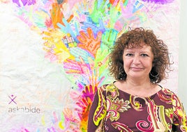 Arias, junto a un mural elaborado por las usuarias de la entidad, que ofrece diferentes servicios.