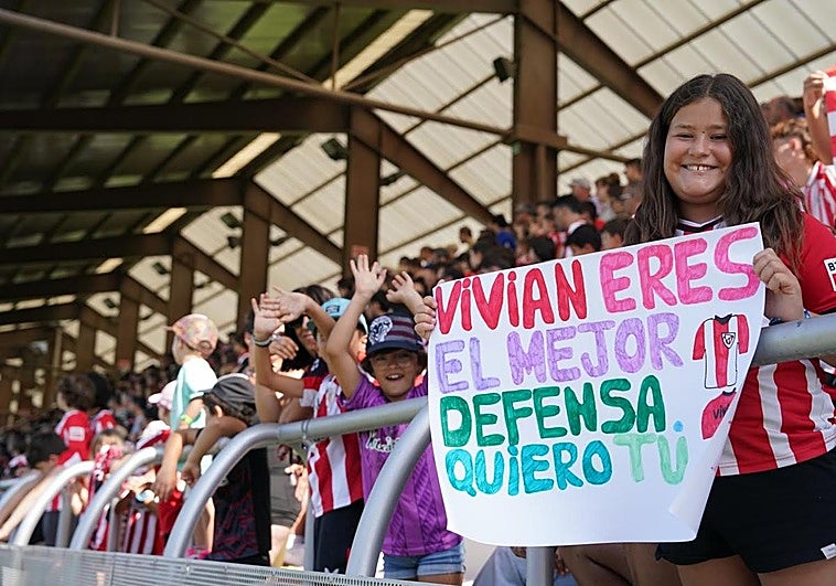 Una niña en la grada muestra un mensaje para Vivián.