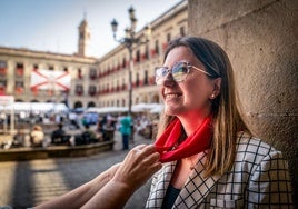La concejala socialista María Nanclares se coloca el pañuelo de fiestas en la plaza de España.