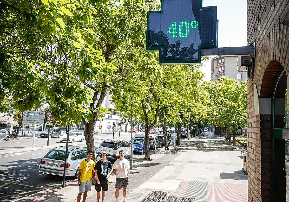 Tres jóvenes observan la temperatura que registró este domingo un termómetro de Vitoria.