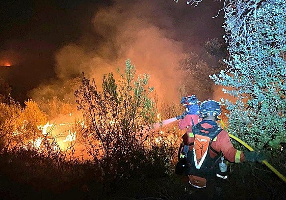 Dos agentes de la Unidad Militar de Emergencias (UME) trabajan en las labores de extinción del incendio en Tres Cantos, Madrid.