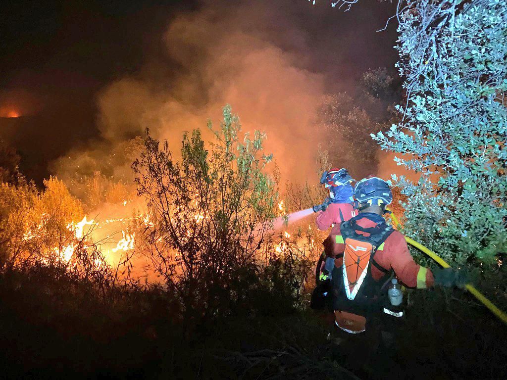 Dos agentes de la Unidad Militar de Emergencias (UME) trabajan en las labores de extinción del incendio en Tres Cantos, Madrid.