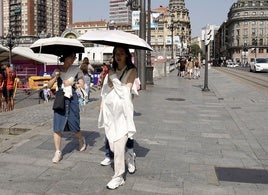 Varias mujeres se protegen del sol con un paraguas en el puente del Arenal.