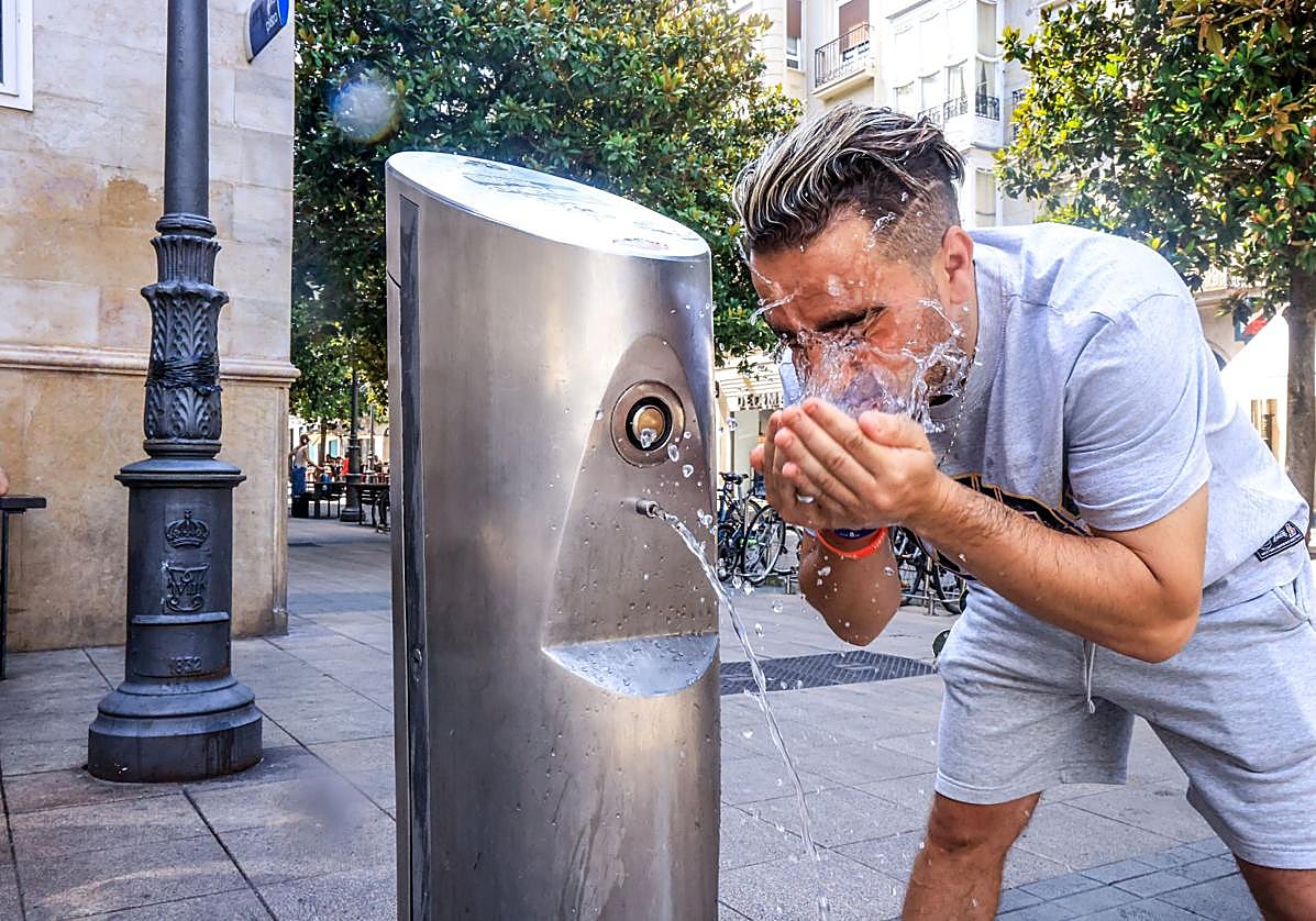 Un hombre se refresca con una fuente ante la ola de calor.