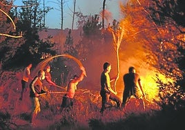 Unos vecinos intentan extinguir las llamas de un incendio forestal en Vilar de Condes, en la provincia de Ourense, en Galicia.