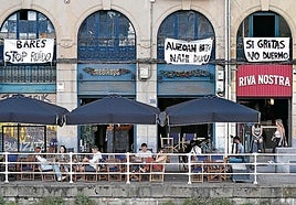 Clientes en las terrazas del Muelle de Marzana, bajo los carteles reivindicativos de los vecinos.
