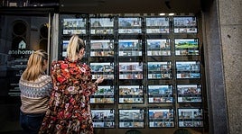 Dos mujeres observan el escaparate de una inmobiliaria.