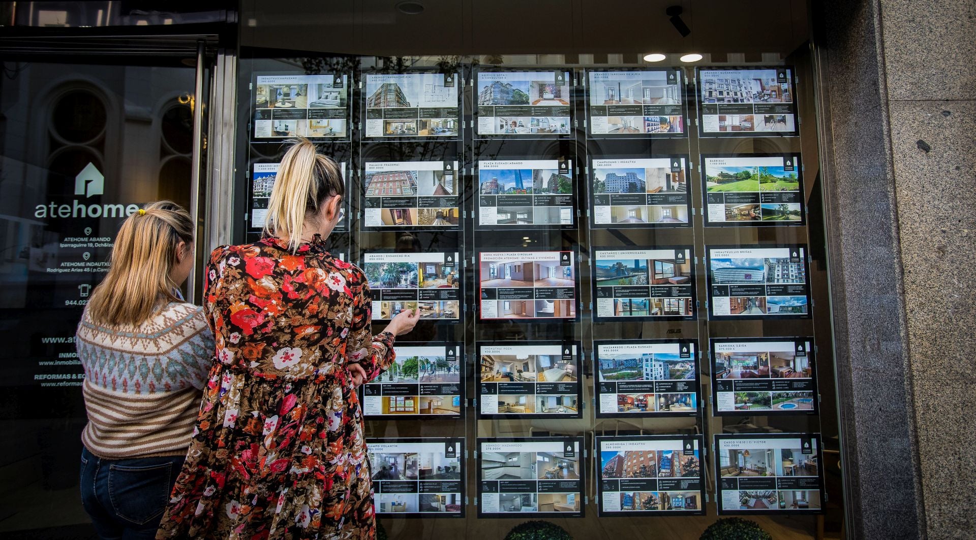 Dos mujeres observan el escaparate de una inmobiliaria.