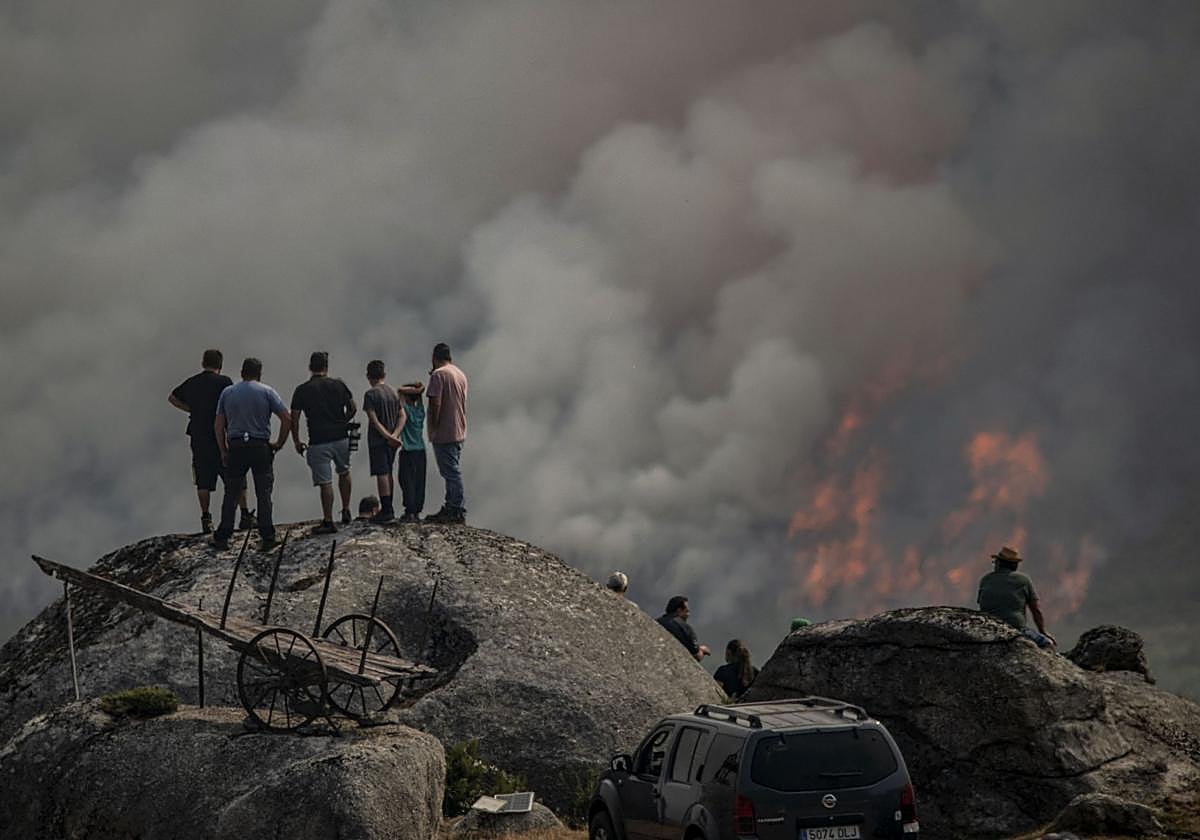 Varias personas observan el incendio forestal declarado este lunes en Avión (Ourense).