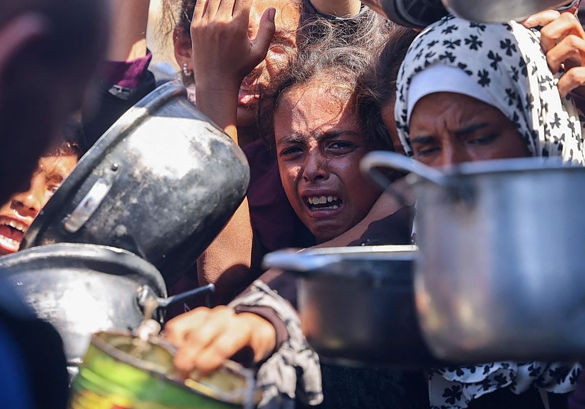Palestinos se agolpan para recibir raciones de comida de un comedor social en Khan Yunis, al sur de la Franja de Gaza, el 27 de agosto de 2025.