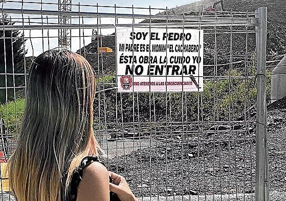 Una vecina observa el cartel colocado por el hijo de 'El Cachabero' en una obra.