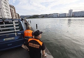 Dos integrantes de Protección Civil vigilan la Ría a la altura de Erandio, con Rontegi al fondo.