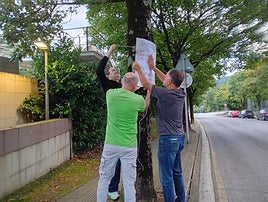 Varios representantes del grupo ecologista Sagarrak colocan un cartel contra la tala de árboles en Abaroa, que no seguirá adelante.