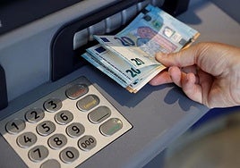 Una persona saca dinero de un cajero de una entidad bancaria.