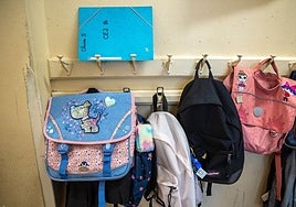 Mochilas colgadas de la pared de una escuela.