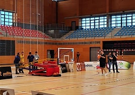 Varias personas trabajan en reparar la canasta durante el calentamiento.