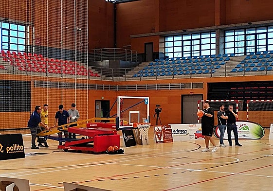 Varias personas trabajan en reparar la canasta durante el calentamiento.