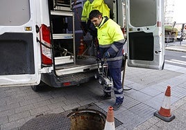 Dos operarios se disponen a realizar tareas de mantenimiento en el alcantarillado.