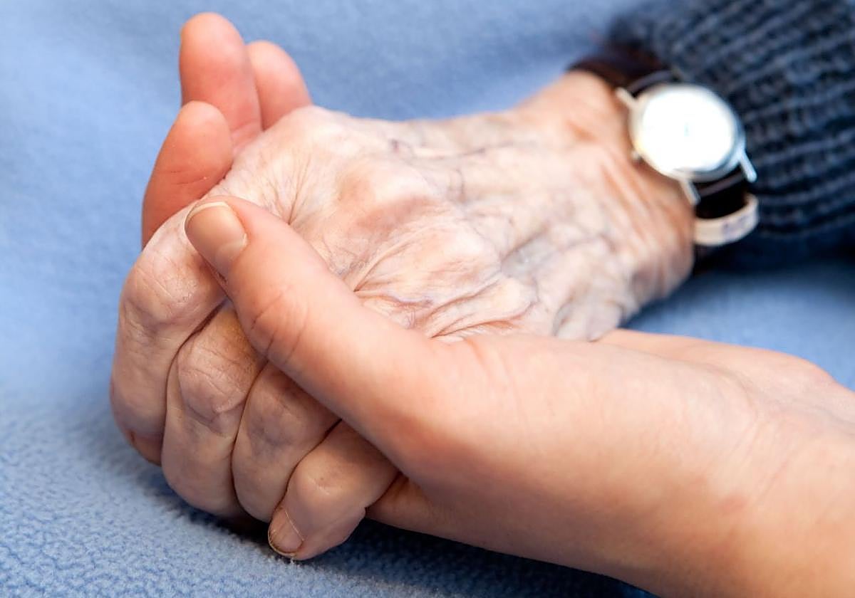 Una mano joven sostiene la mano de una persona mayor.