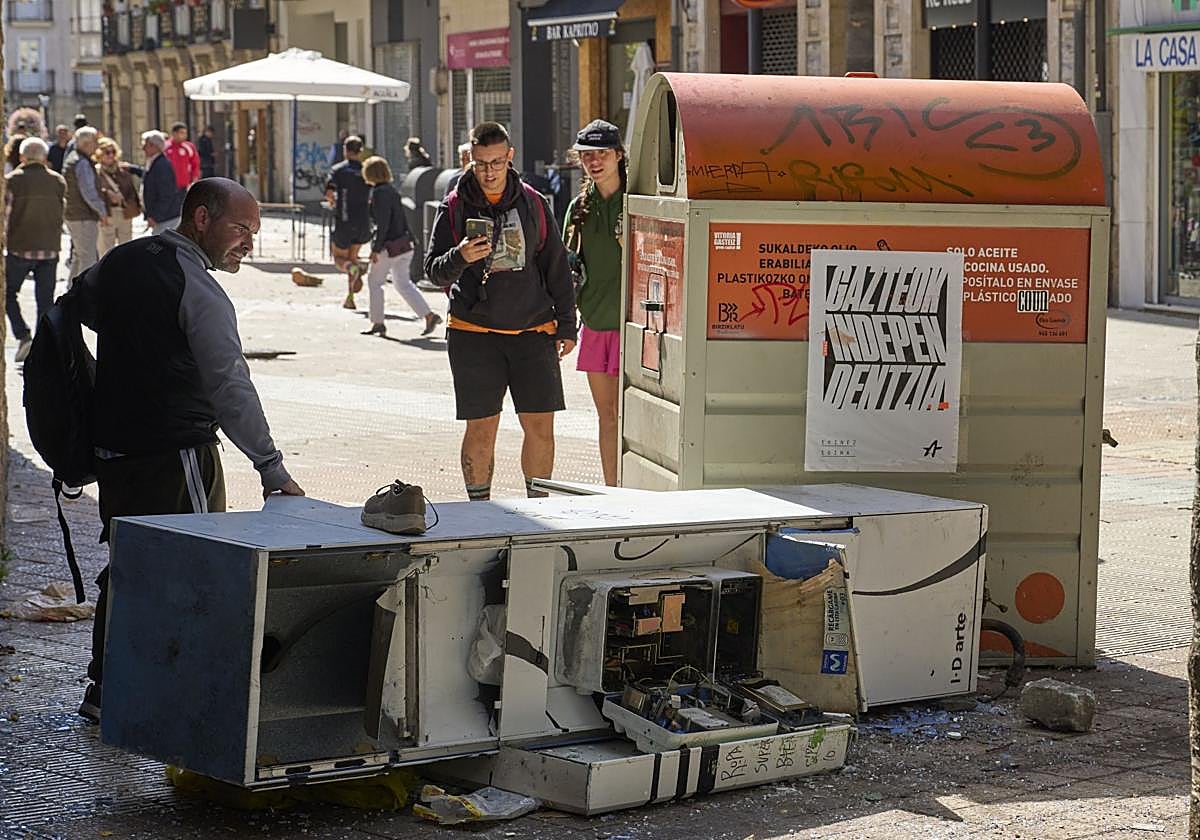 Varias personas observan los destrozos ocasionados en la calle Diputación de Vitoria.
